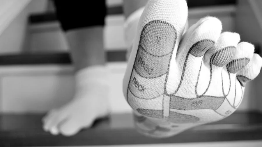Person applying foot cream in morning while getting dressed with socks nearby