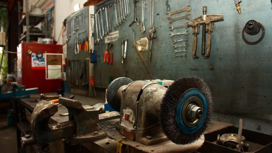 Person applying grease to metal machinery parts during maintenance work