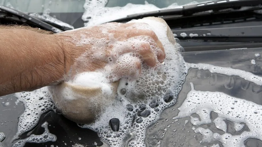 Person applying protective coating to vehicle components during routine maintenance work