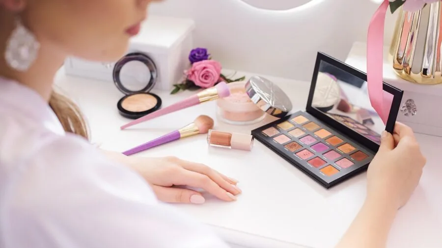 Person applying richly pigmented eyeshadow while looking in mirror, demonstrating color payoff and application technique