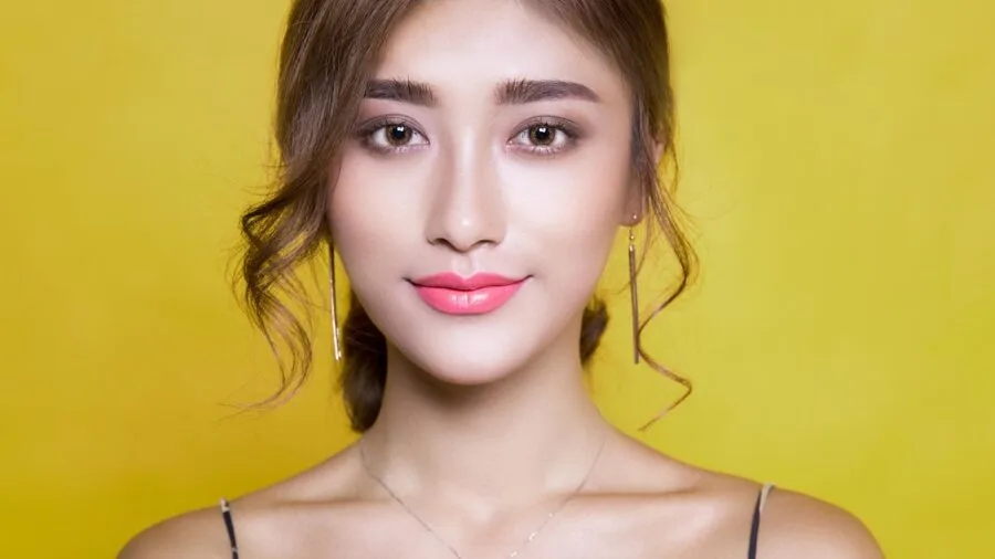 Person applying skincare product to face in natural bathroom lighting, focusing on oily skin type preparation