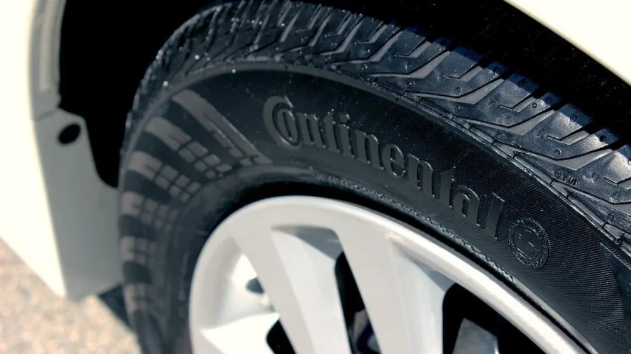 Person applying tire care product to vehicle wheel during outdoor car maintenance session
