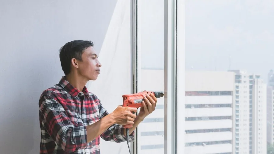 Person applying weatherproofing materials to door frame in residential home