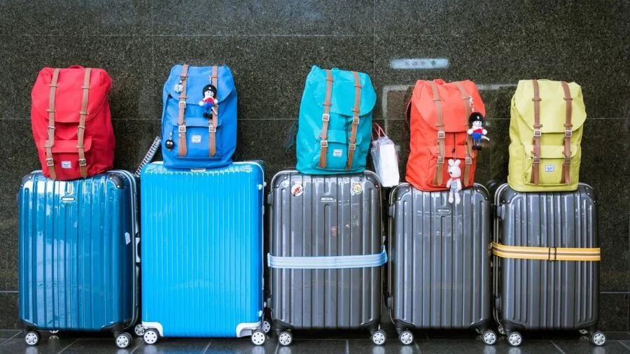 Person arranging clothes and items in open suitcase for packing trip
