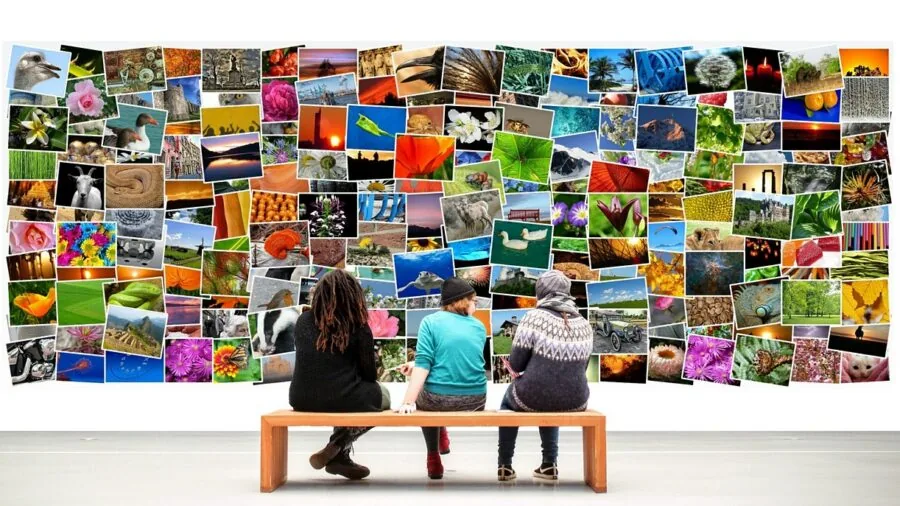 Person arranging multiple framed photographs on living room wall for home decoration