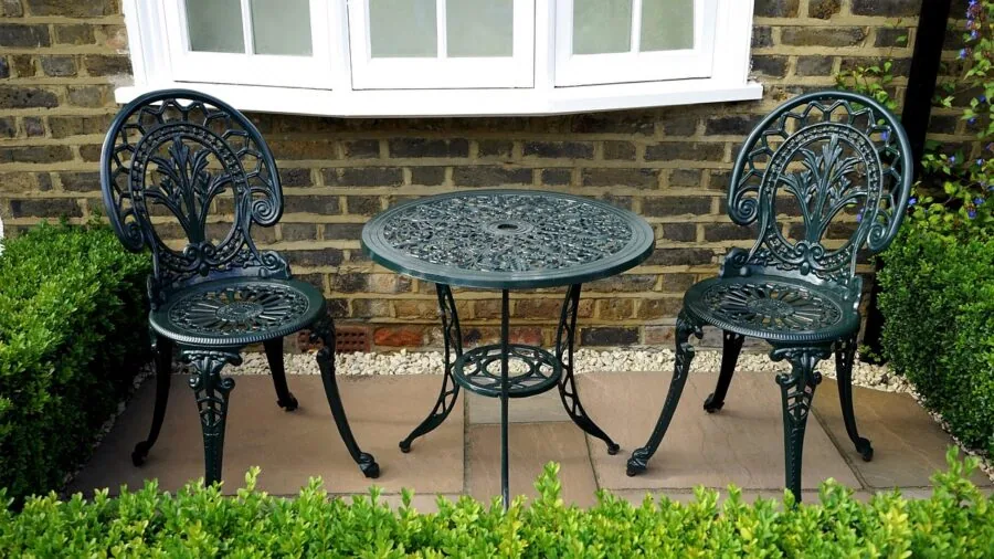 Person arranging outdoor patio furniture and lighting in backyard during evening twilight hours