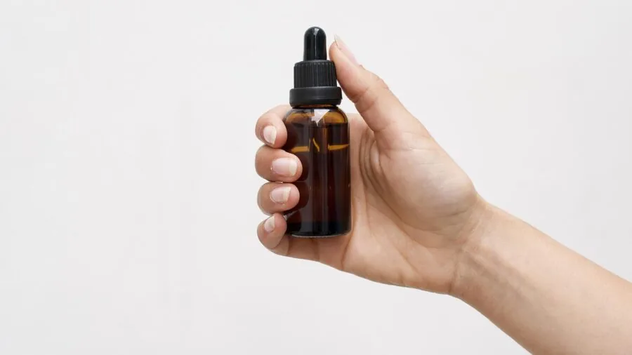 Person arranging various supplement bottles and natural ingredients on a wooden surface for organization