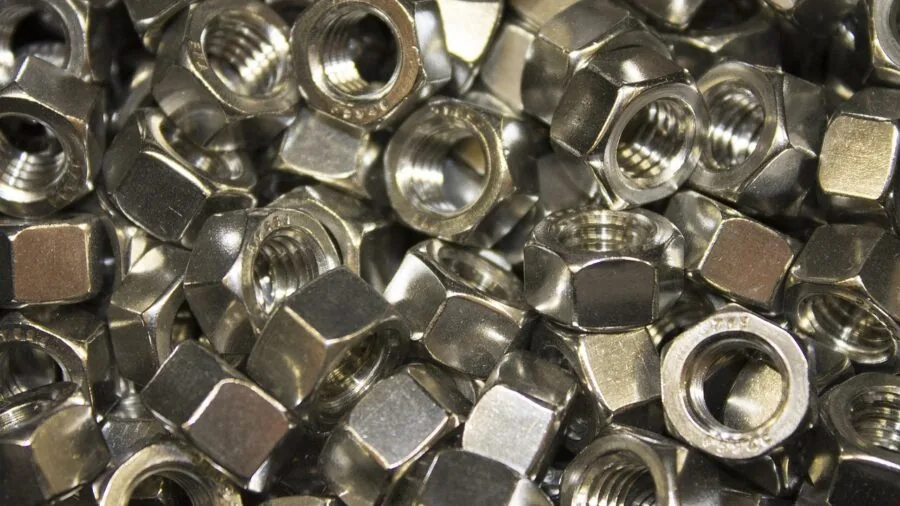 Person assembling metal bolts and fasteners on wooden workbench with tools