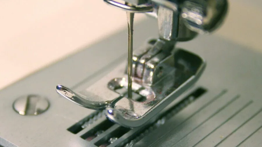 Person at sewing table carefully managing iron while quilting, demonstrating safe crafting practices