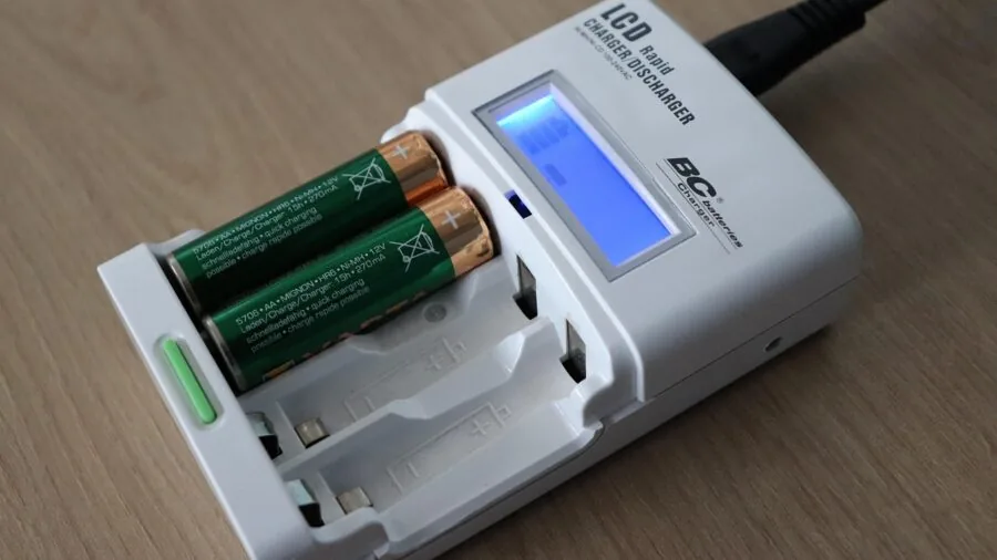 Person attaching battery terminal connectors to vehicle battery in garage setting