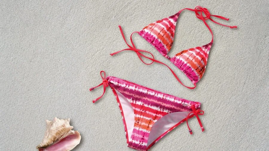 Person browsing colorful casual beachwear and summer outfits at a clothing store
