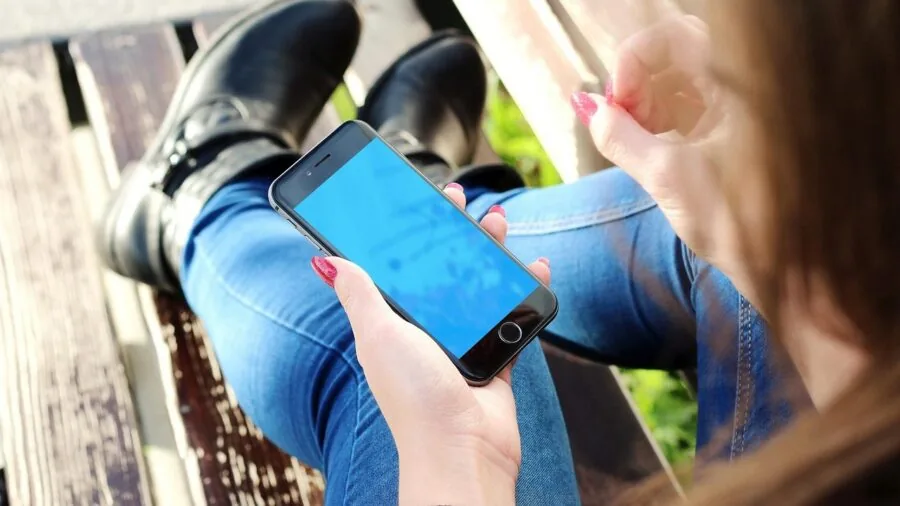 Person carefully aligning and installing a protective screen film on smartphone with precision
