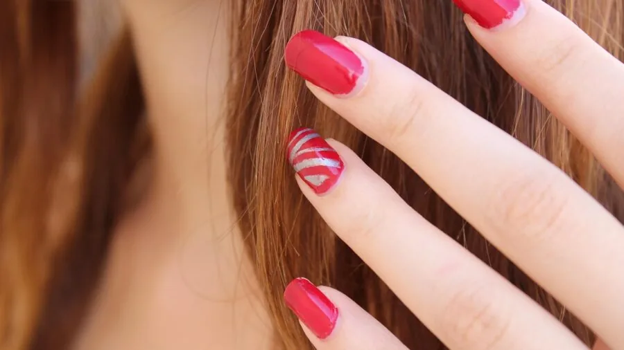 Person carefully applying cuticle oil to fingernails in natural daylight setting