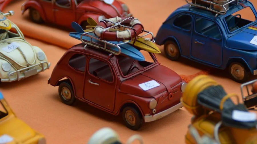 Person carefully arranging small diecast model cars on display shelf with focused attention