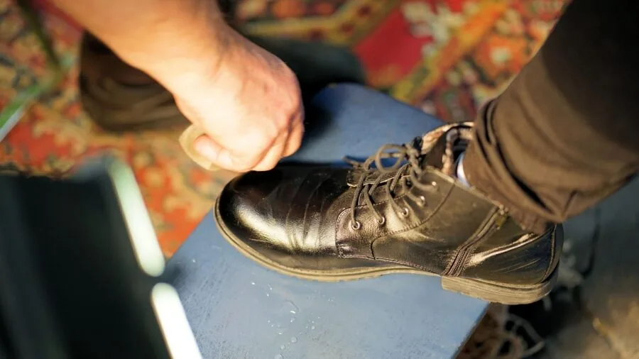 Person carefully cleaning and maintaining a leather item with a cloth, demonstrating proper leather care techniques