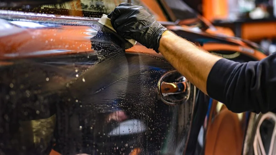 Person carefully cleaning car interior dashboard and vents with detail brush