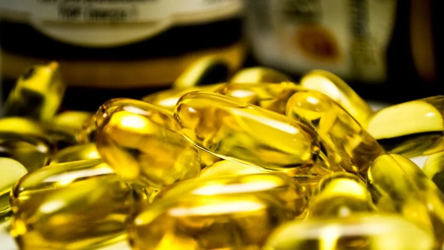 Person carefully examining vitamin supplement bottle label while researching nutritional information at home