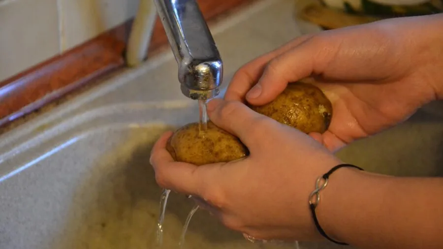 Person carefully hand washing crystal glasses in warm soapy water at kitchen sink