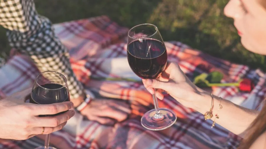 Person carefully hand washing wine glasses at kitchen sink with warm soapy water