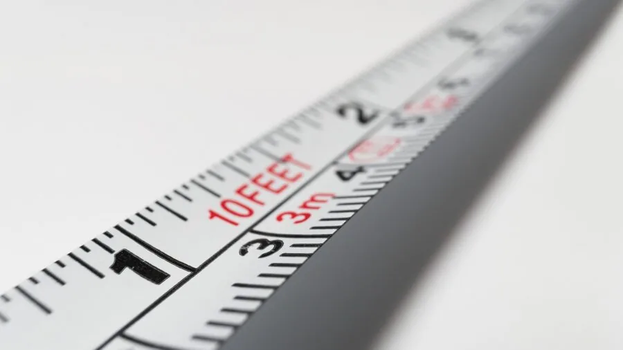 Person carefully measuring their foot length with a measuring tape for proper shoe sizing