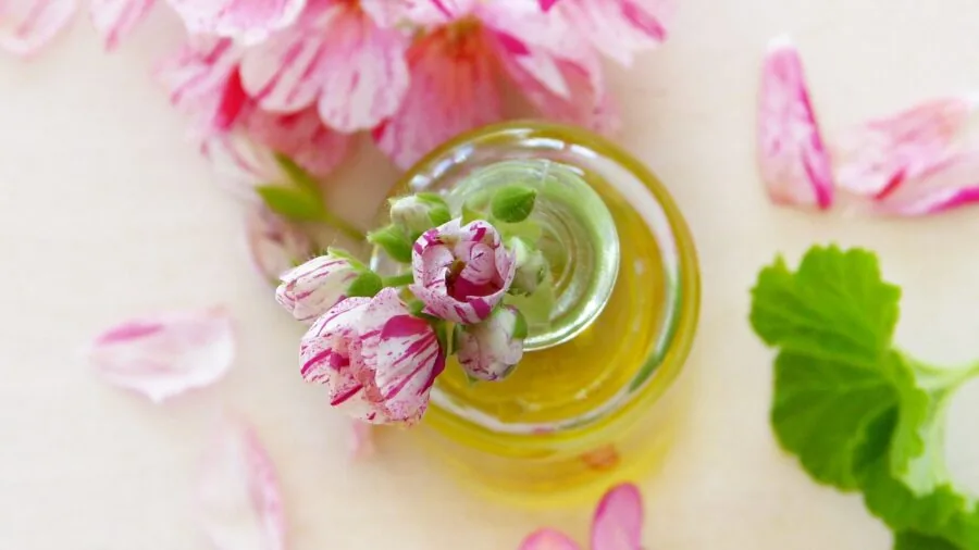 Person carefully mixing and layering essential oils in a bright, calm workspace with natural light