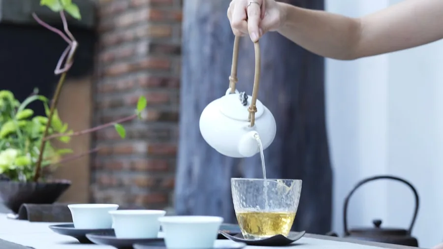 Person carefully pouring hot water into teacup, focusing on precise temperature brewing technique