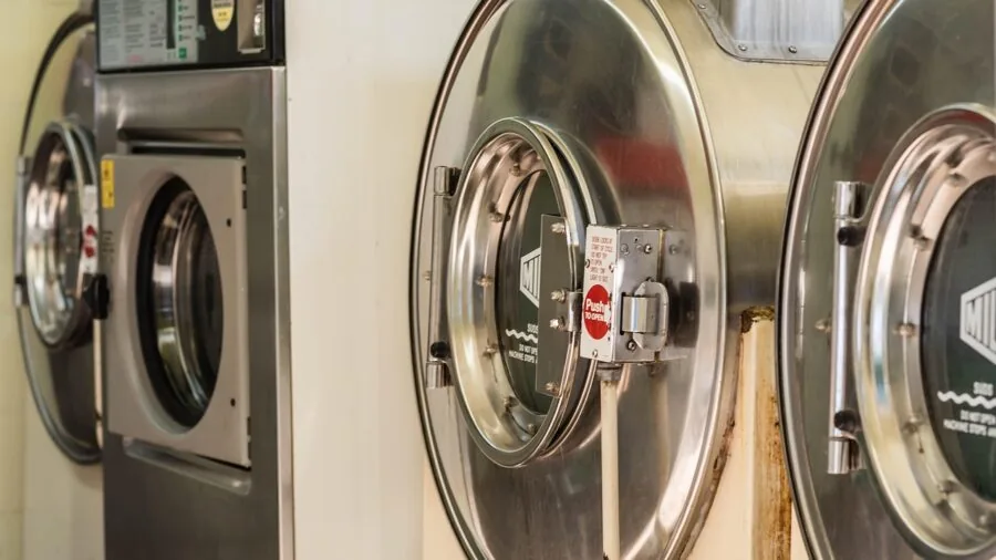 Person carefully removing clothes from dryer to demonstrate proper garment care and washing habits