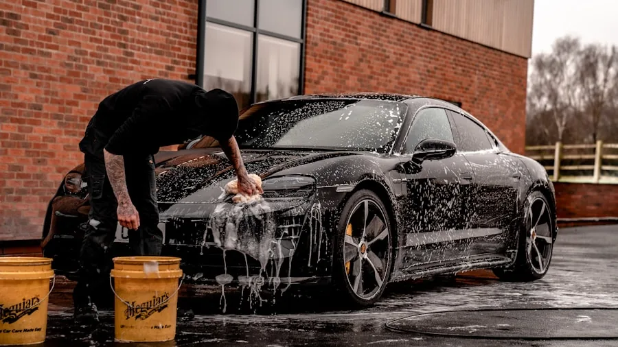 Person carefully washing and polishing a car exterior with attention to detail and trim work