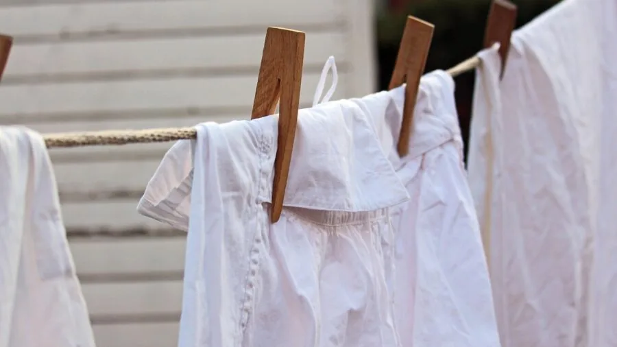 Person carefully washing white cotton sheets in washing machine, demonstrating proper laundry care for sheet durability