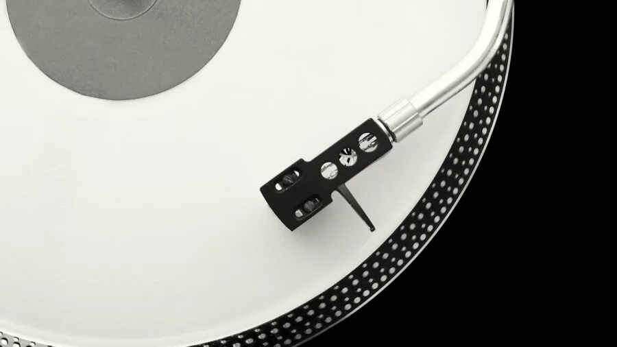 Person carrying a retro suitcase-style record player while traveling outdoors in natural daylight
