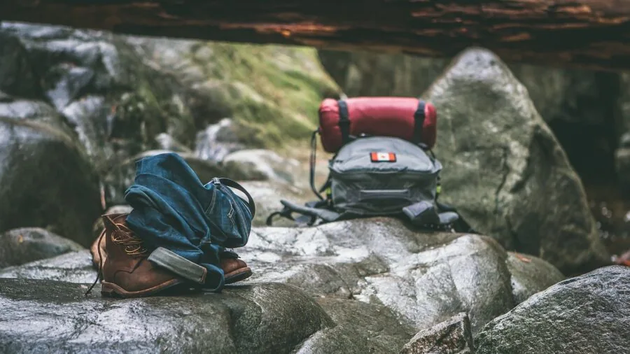 Person carrying portable solar generator on hiking trail through forest landscape