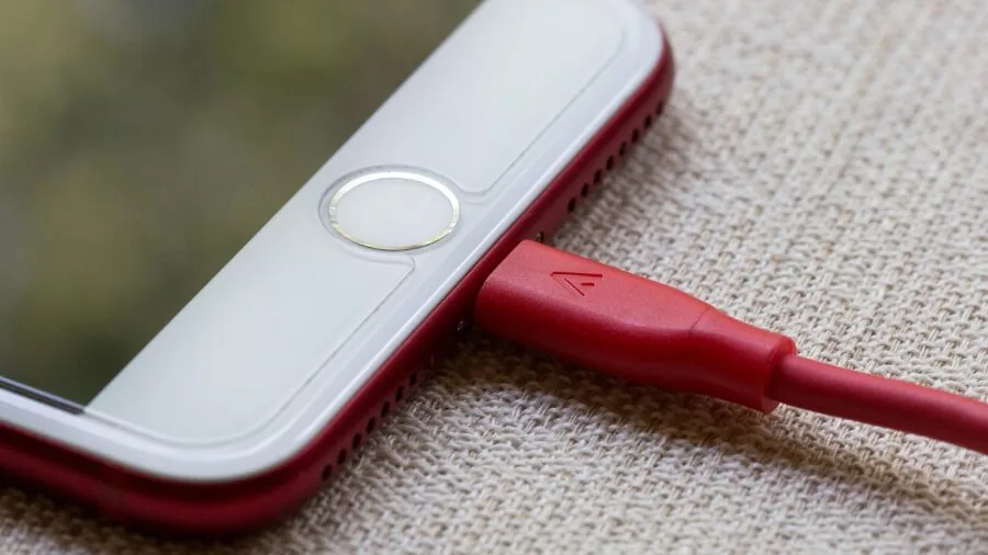 Person charging a portable device with a modern USB cable in a casual everyday setting
