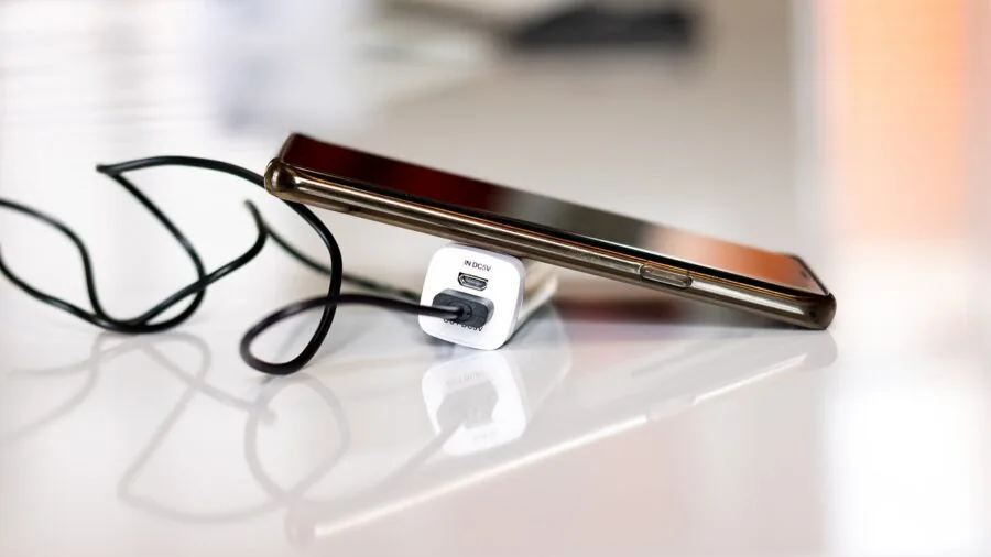 Person charging mobile device quickly with portable power bank during travel