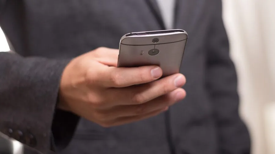 Person charging phone wirelessly on desk with modern tech setup