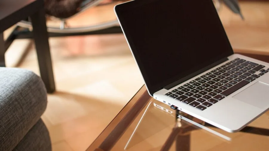 Person charging wireless mouse with USB cable at home desk workspace