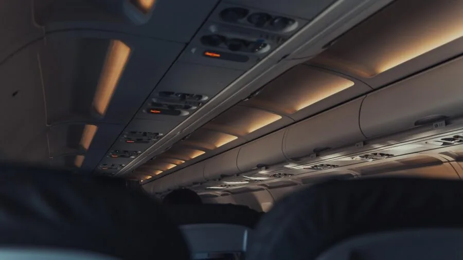 Person checking luggage dimensions against airplane overhead bin space during travel