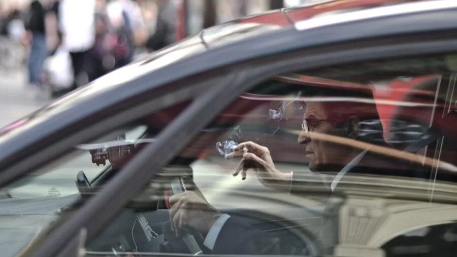Person checking mobile phone while sitting in driver's seat of vehicle