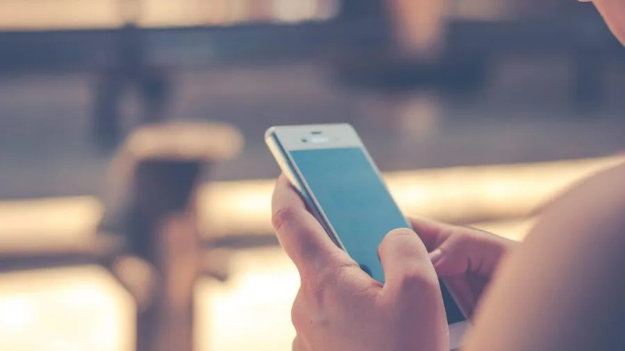 Person checking smartphone app while standing outdoors in urban setting