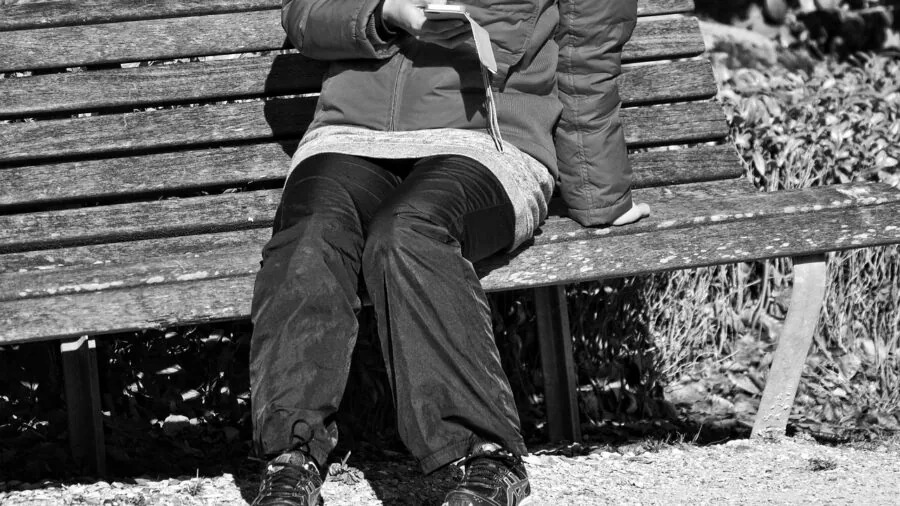 Person checking smartphone battery percentage while traveling with backpack and luggage