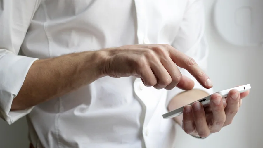 Person checking smartphone in contemporary kitchen with stainless steel appliances