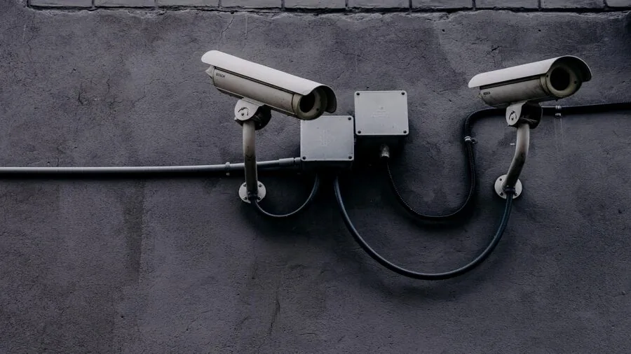 Person checking wireless security camera battery status on smartphone outdoors