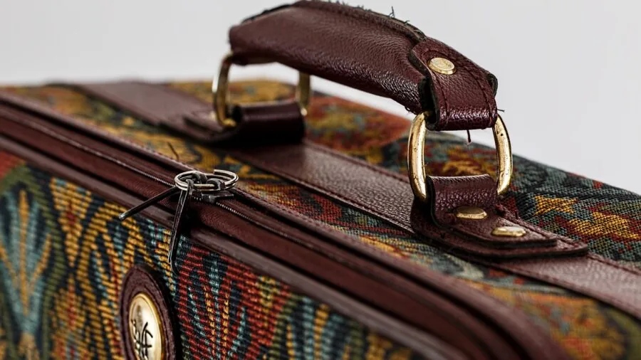 Person checking zipper closure on crossbody bag while traveling in urban environment