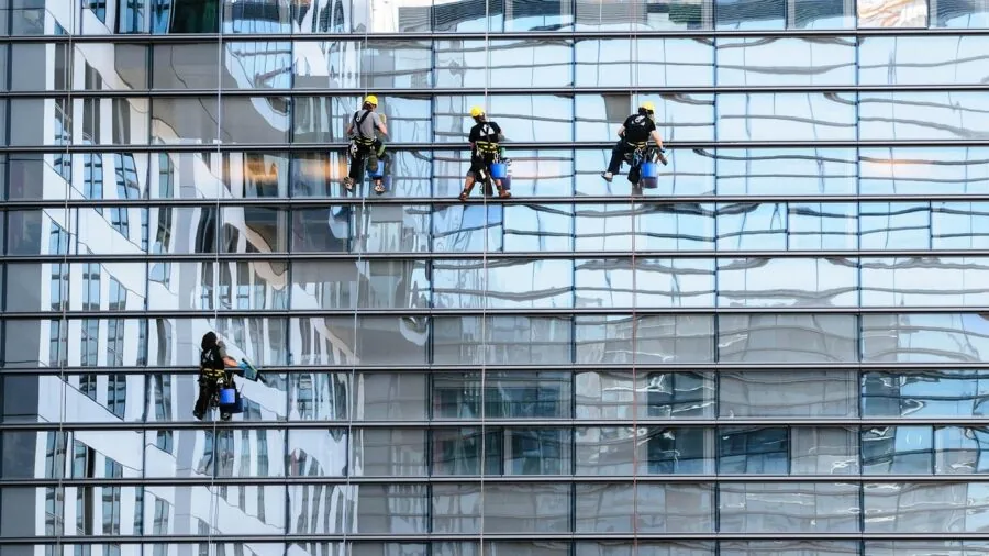 Person cleaning a large window with a squeegee, showing proper technique for streak-free results