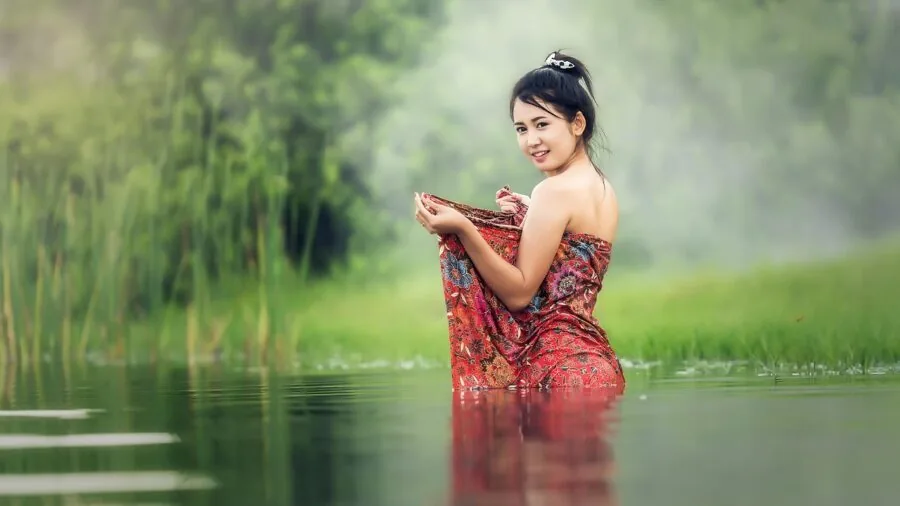 Person cleaning camping dishes in natural water source during outdoor wilderness trip