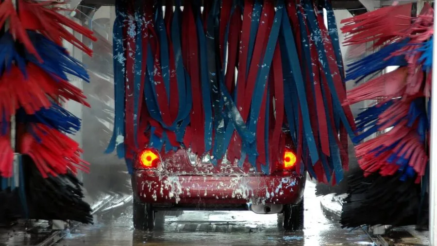 Person cleaning car interior filter, hands performing vehicle maintenance in natural light