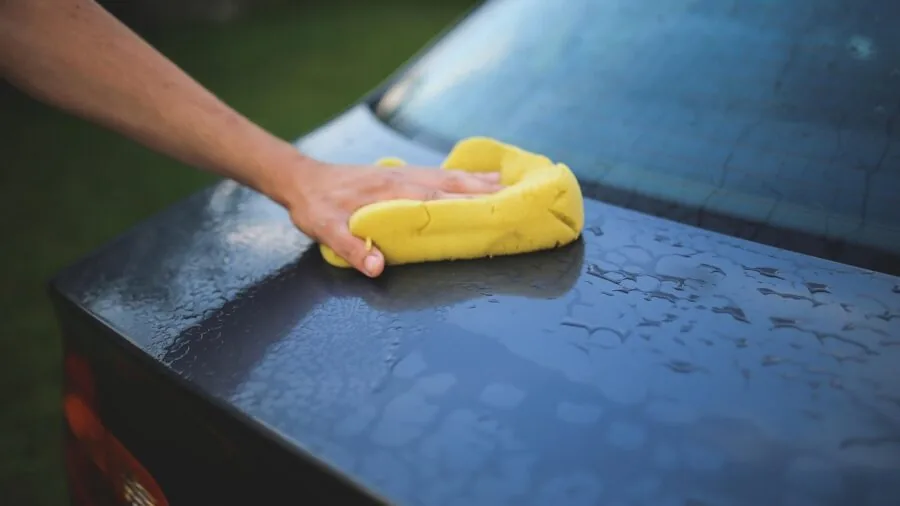 Person cleaning car interior with various detailing brushes and tools in natural light