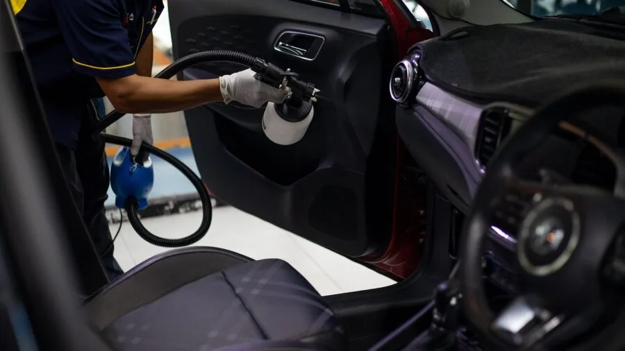 Person cleaning inside vehicle interior with focus on dashboard and upholstery care