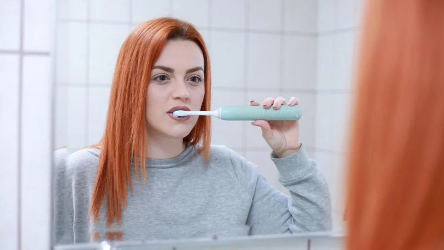 Person cleaning teeth at bathroom sink during morning hygiene routine