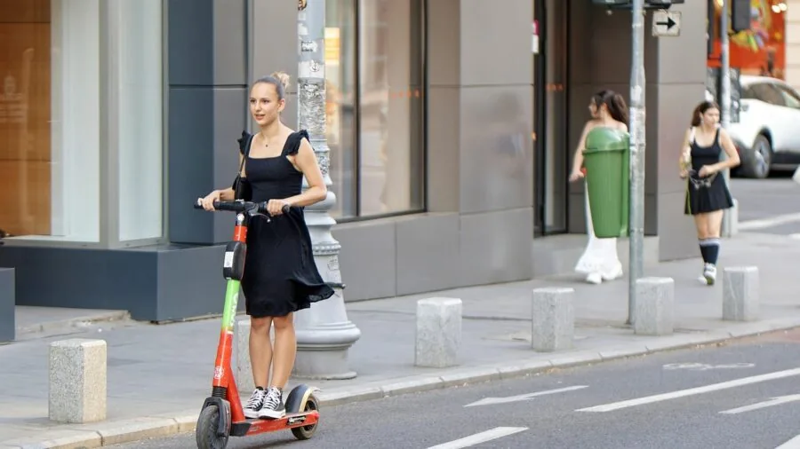 Person commuting on electric scooter through city street during daytime