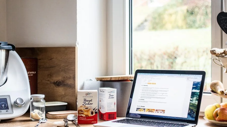 Person comparing kitchen tools and prices while planning meals in a home kitchen setting